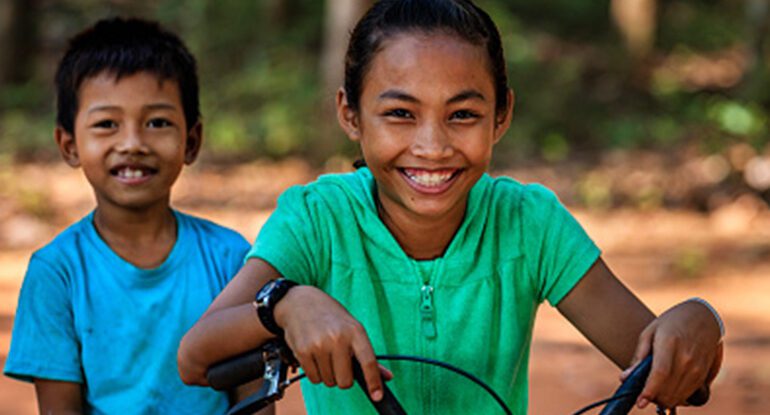 A young girl smiles while riding her bike.