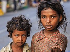 Two children standing next to each other on a street.